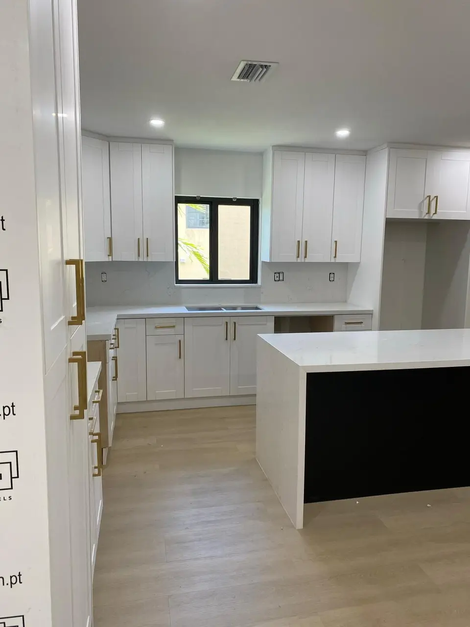 White shaker kitchen with brass pulls and a white waterfall island