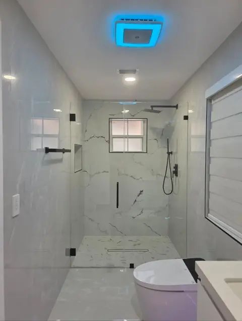 Frameless glass shower with marble-look porcelain walls and black fixtures