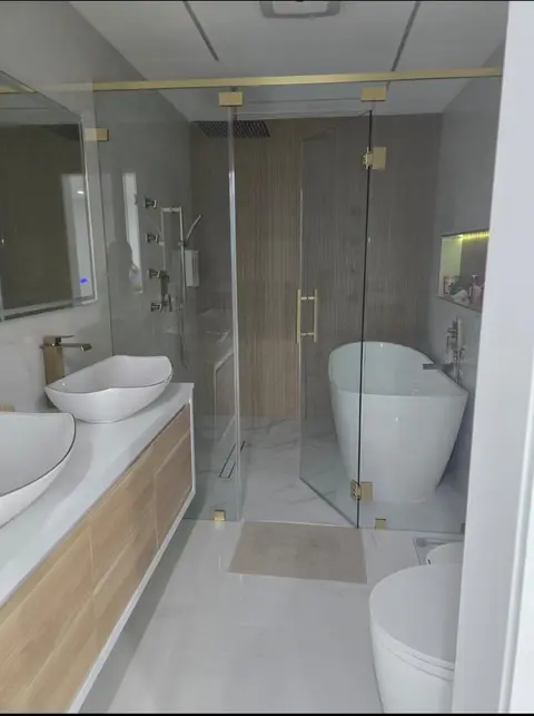 Bathroom with vessel sinks, glass shower enclosure and freestanding tub