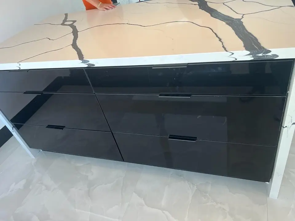 Glossy black vanity drawers under a white marble-look waterfall countertop