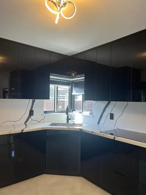 Glossy black corner kitchen with marble-look countertops