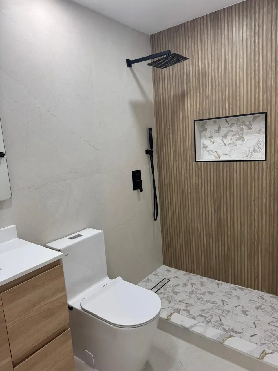 Shower with wood-look slat wall, large-format beige panel, black fixtures and linear drain