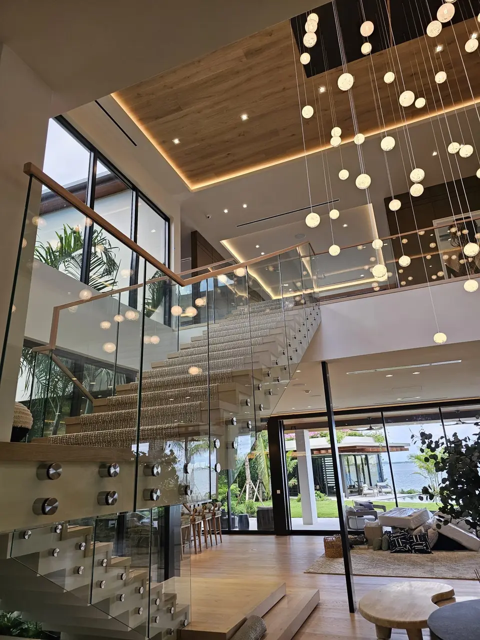Staircase with glass railing, brass handrail and cascading chandelier